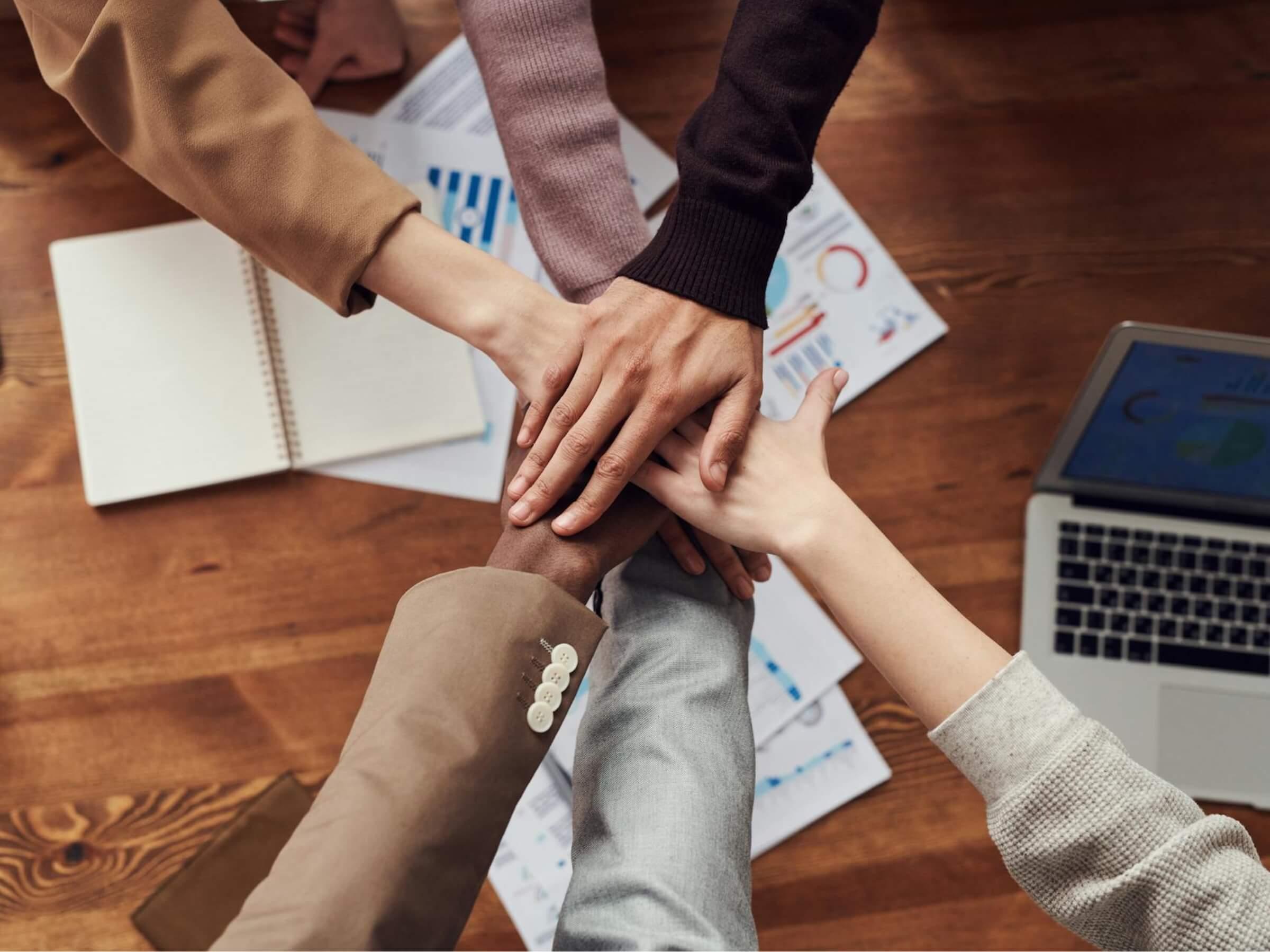 a diverse team of people all putting their hands together